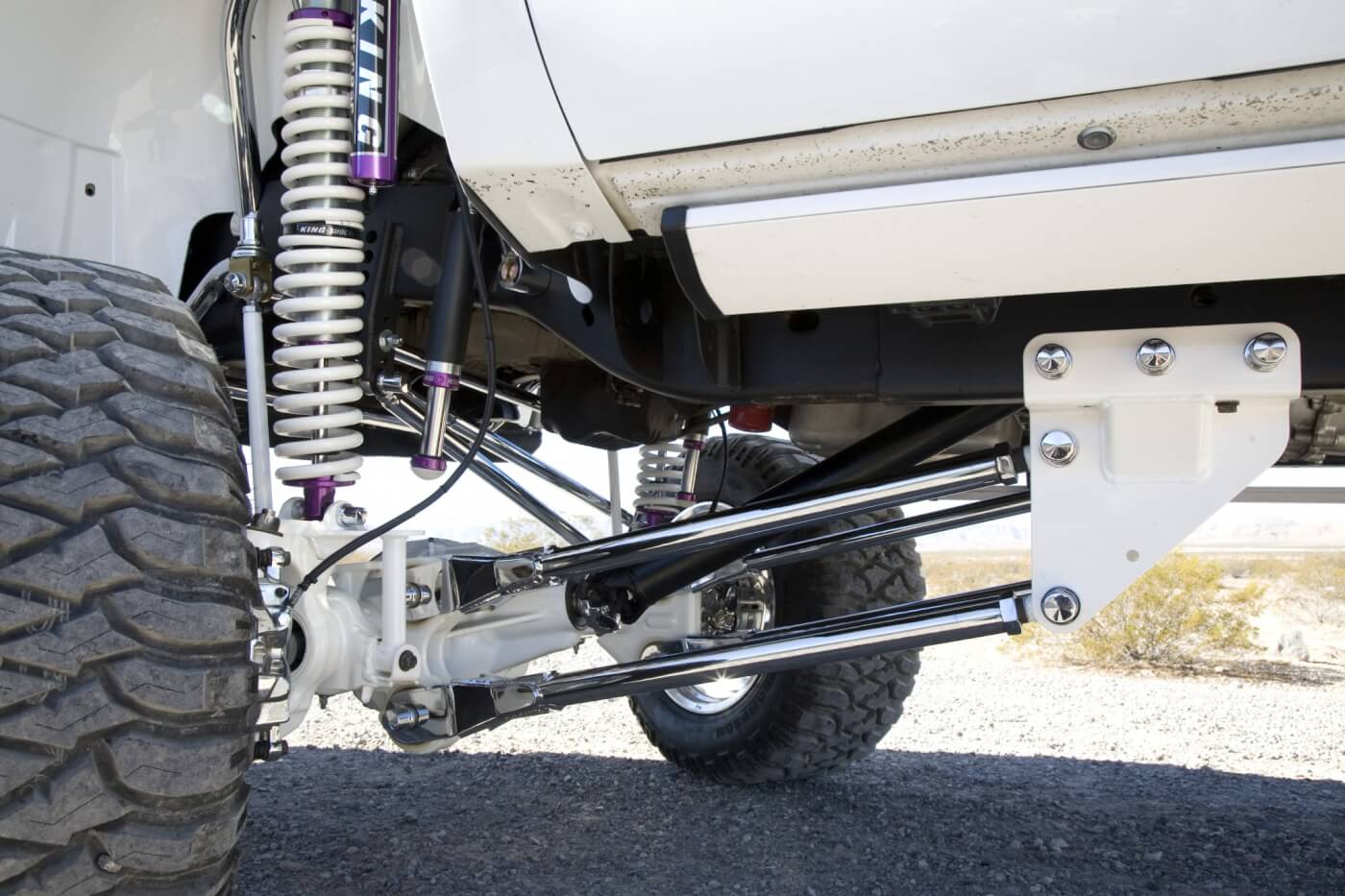 The back half of the front suspensions can be seen here. Notice that frame brackets have been painted white, while the upper and lower control arms are chrome plated. Look closely and you can also see the Amp Research steps that have been painted white to match the truck. 