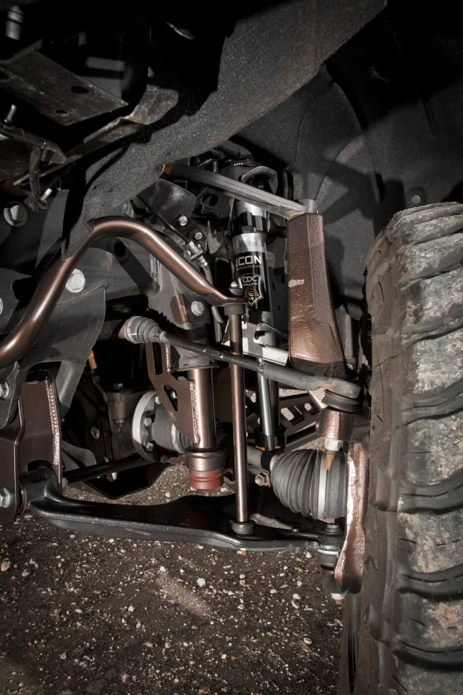 The McGaughys suspension kit is virtually a bolt-on system, No cutting or grinding of the front or rear differential is required, and only a few new holes are drilled. Here you see part of the front suspension. Notice the A-arm lowering bolts, new bump stop extensions, new steering knuckles (spindles) and Icon shocks. All are powder coated to match the body color.