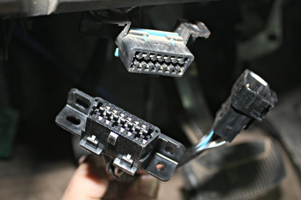 4. The factory OBD-II port will be removed from its mounting location under the dash and plugged into the female end of the OBD-II pigtail in the BD harness. The new male end of the harness will be fastened to the stock location under the dash.