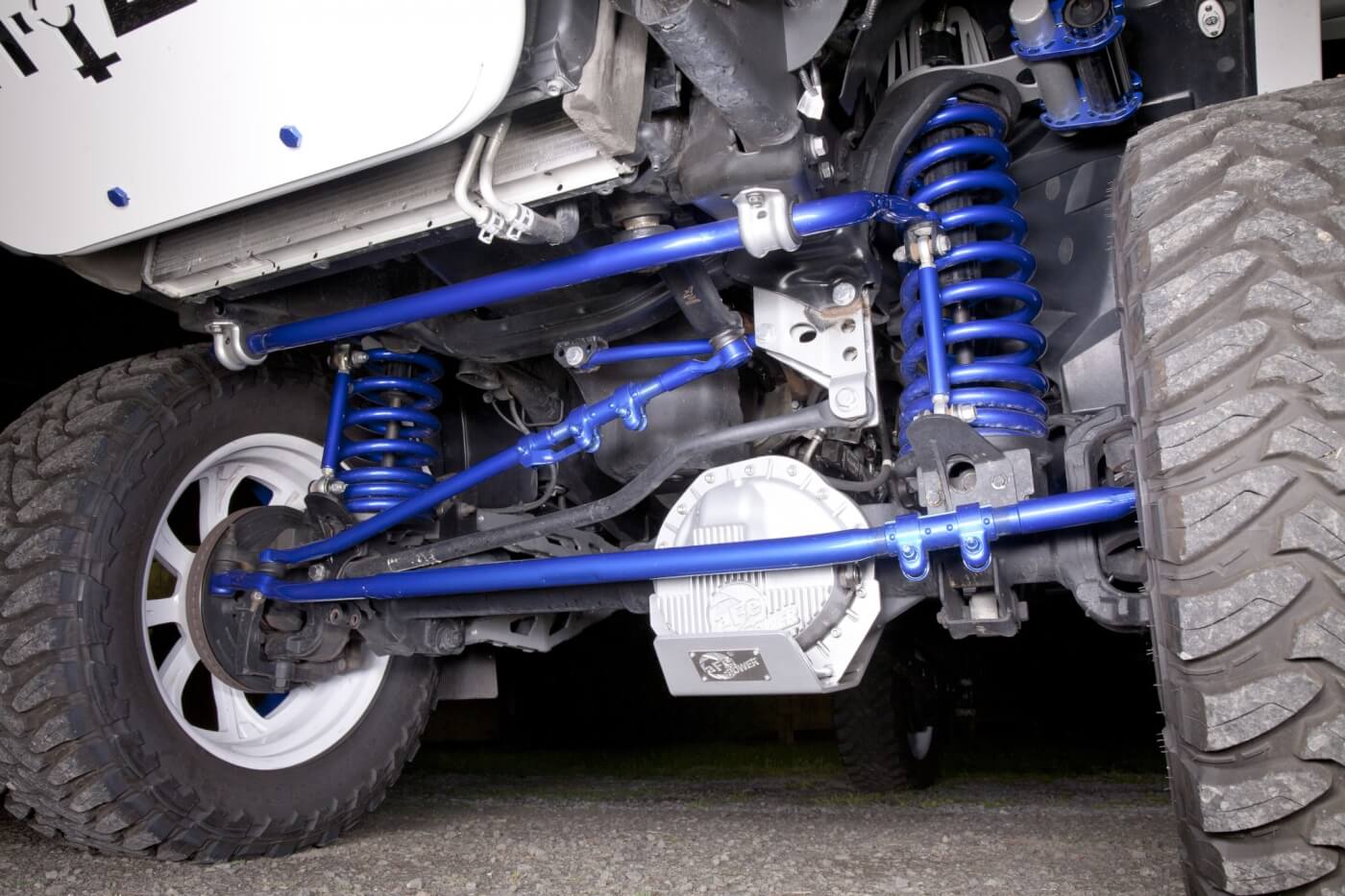 A peek underneath reveals a heavily detailed lifted suspension system by Pure Performance coated in bright blue by Applied Coatings.