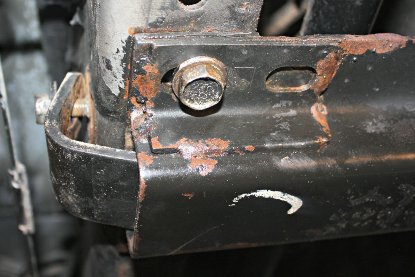 4. After placing a floor jack under the transmission to support its weight, the transmission cross member can be taken out. It is bolted to the frame rails with four large 18mm bolts, two on each side. The outer L-shaped bracket will need to be removed as well. 