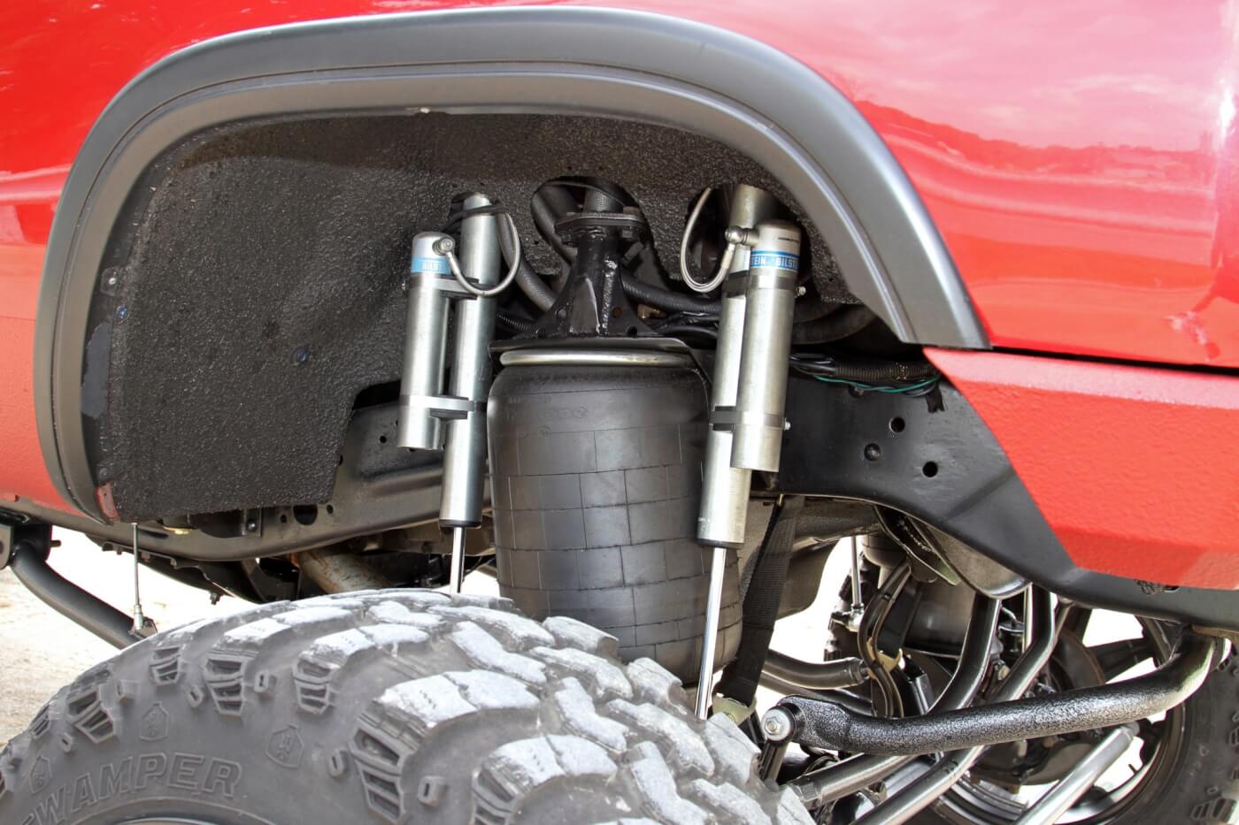 Each front corner of the truck is treated to a pair of Bilstein shocks on custom mounts flanking the Firestone airbag. Notice the upper support that ties the bag mounts together side to side over the engine.