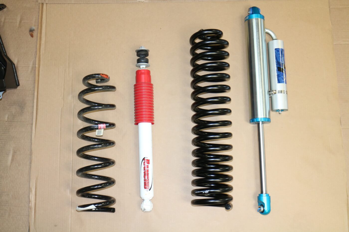 4. The OEM front spring and shock (L) are seen here, compared to the longer Carli springs and remote reservoir shocks. 