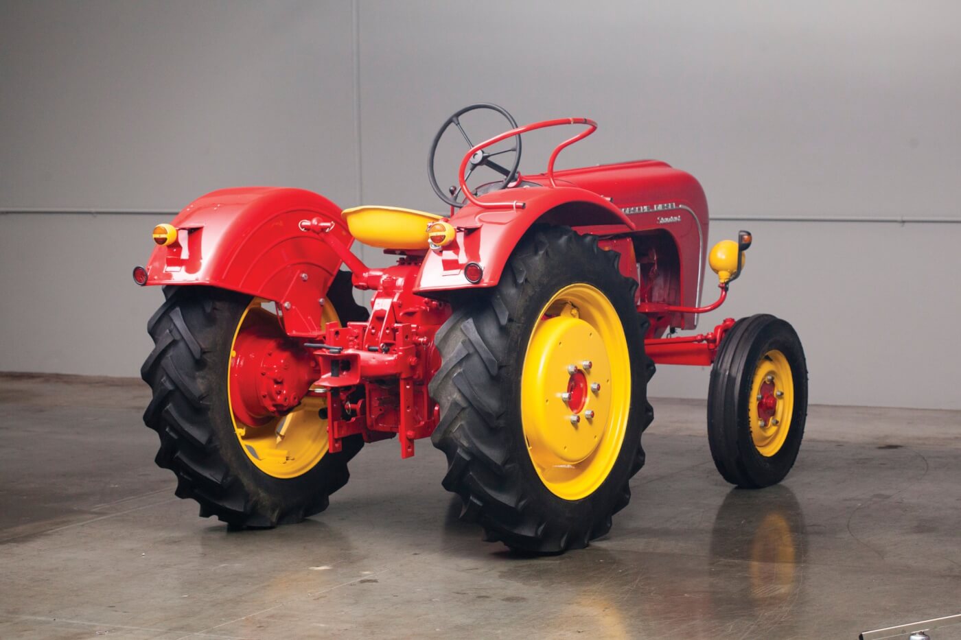 Though a rear three-point hydraulic lift was technically optional, it was so common in the U.S. imports that you could say “every one” had it. This one is missing its lower arms and links but has the adjustable hitch. For the Standard, the lift was a Class II and rated for about 2,800 lbs. The specs say this tractor was rated for a 2-14 mouldboard plow. When you look at specs for the four Porsche-Diesel tractor models, the plow rating is tied directly to the number of engine cylinders, in this case: two bottom for two cylinders. The hoop-like device on the rear fender is the passenger seating area. Not comfortable, but secure.