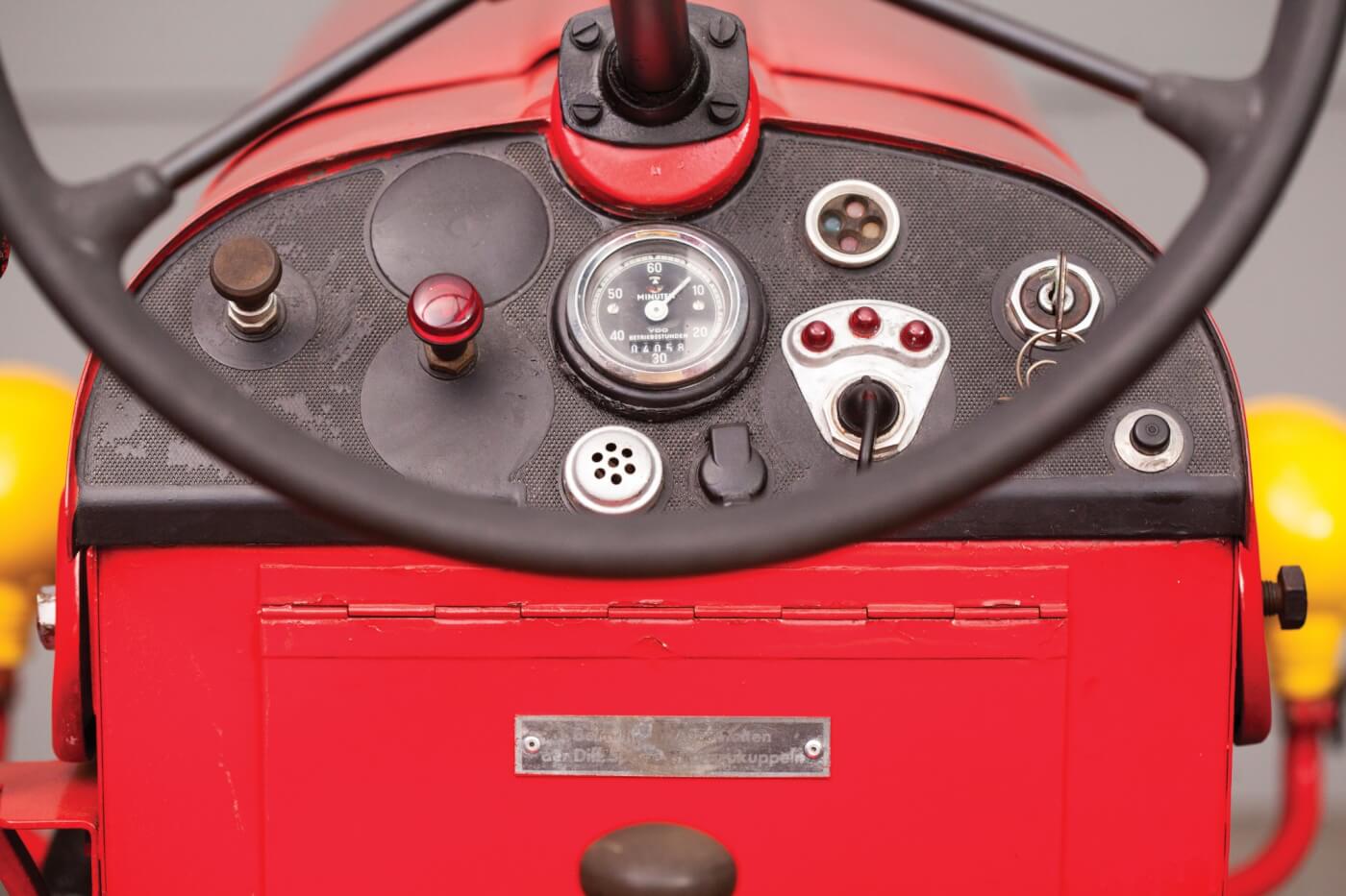 Like many ‘50s tractosr, the dash is typically austere. The horn and turn signal add to the complexity. If the hour meter is original, this tractor only had 4,058 hours at the time of sale. The hinged cover below is a storage compartment.
