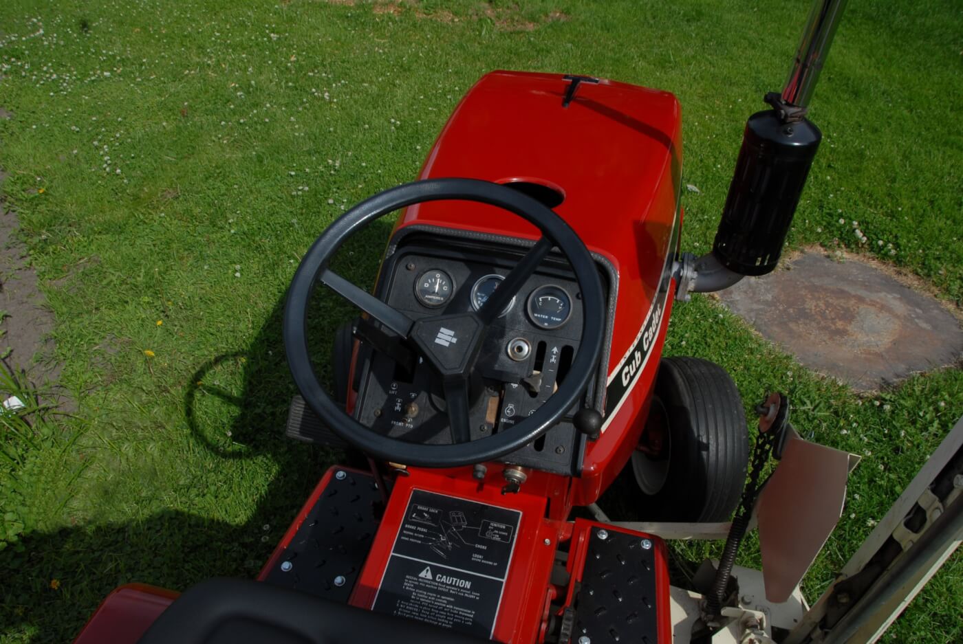 The 782D differs from most lawn tractors its size in having water temp and oil pressure gauges as well as a radiator and a fan. The Kubota diesel has a glow system, albeit an old school one, with a fourth glow plug mounted in the dash and observed through a sight hole just to the right of the steering column. The other controls are largely the same as the other 782s, and the fuel tank is located under the seat.