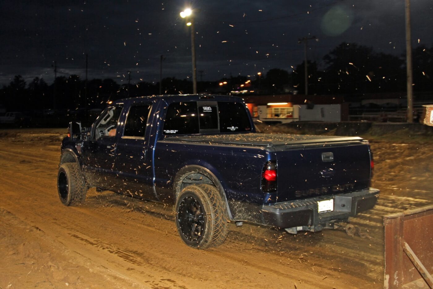The pulling action finished under the lights. Check out the mud flying off the street tires on this 6.4L Super Duty.