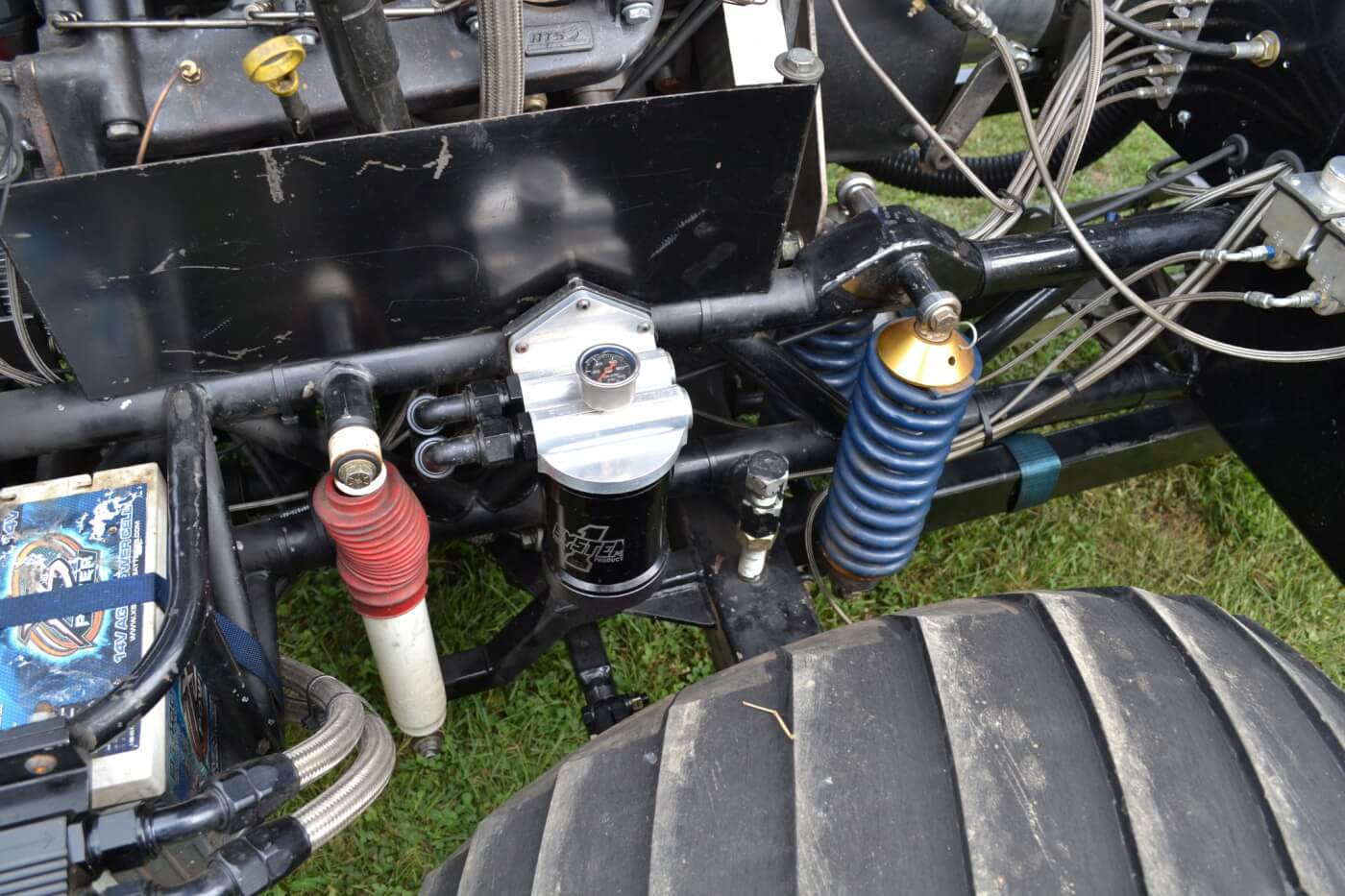 The front suspension came with the Barker-built tube chassis, and Kyle admits he hasn't touched it much over the years. There are two coilovers and one shock per side, which are used to dampen the front axle, which is a mix of military and Rockwell F106 parts. Also visible in the left corner is one of four 14-volt batteries, which Kyle runs to prevent any voltage drop, as the truck's electric over hydraulic steering takes some serious amperage to run.