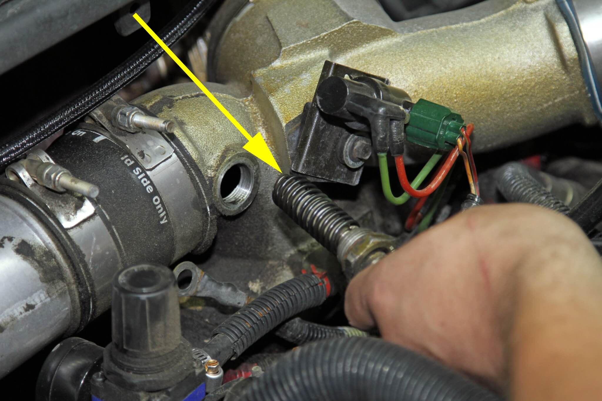 9. The bulky and unnecessary intake heater is removed from the intake and the Driven Diesel plug is installed in its place (see arrows). The plug features a threaded input to install the boost tube port.