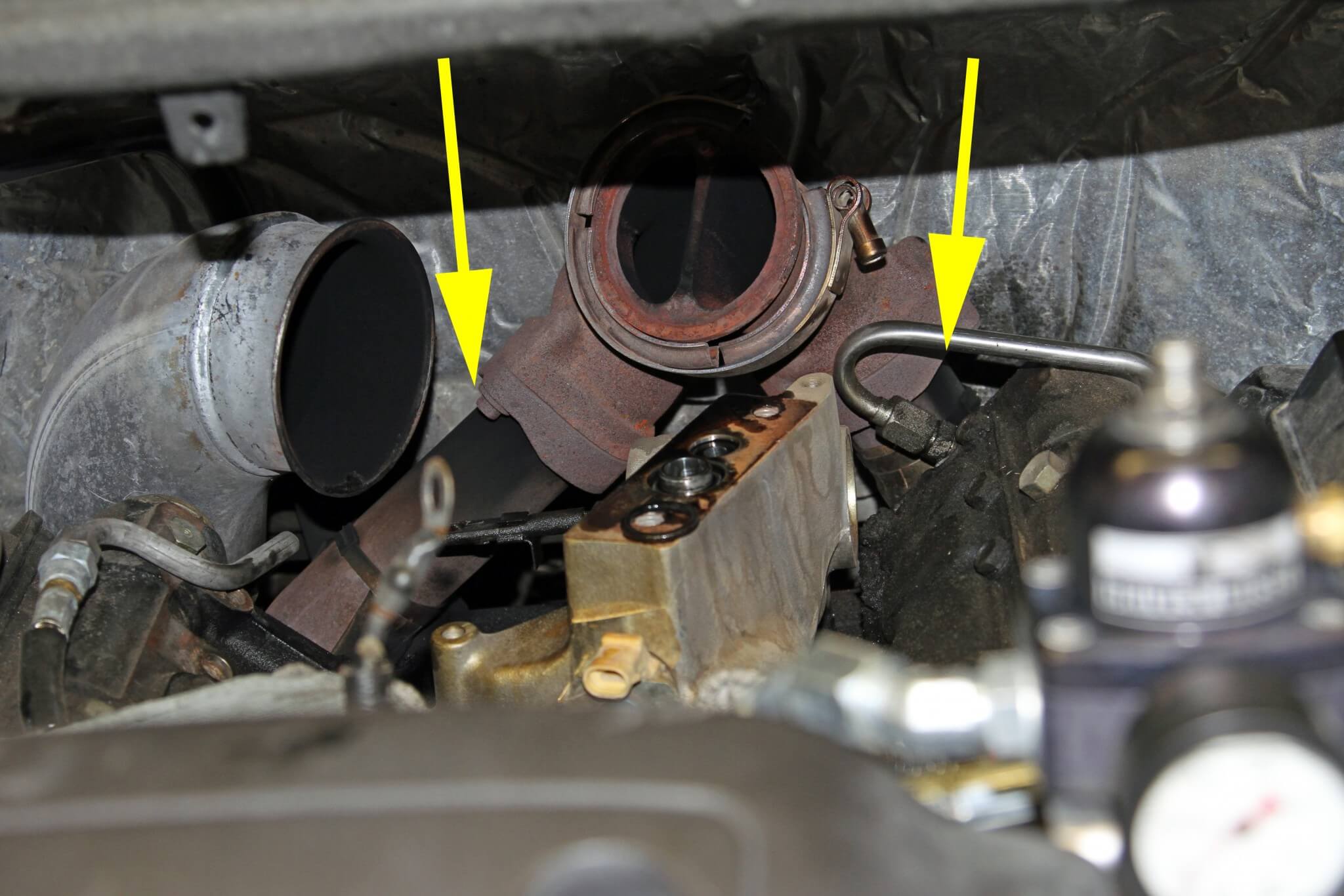 6. With the turbo out of the way you can see the up-pipes and collector. Soot stains on the up-pipes (see arrows) are evidence of severe exhaust leaks.