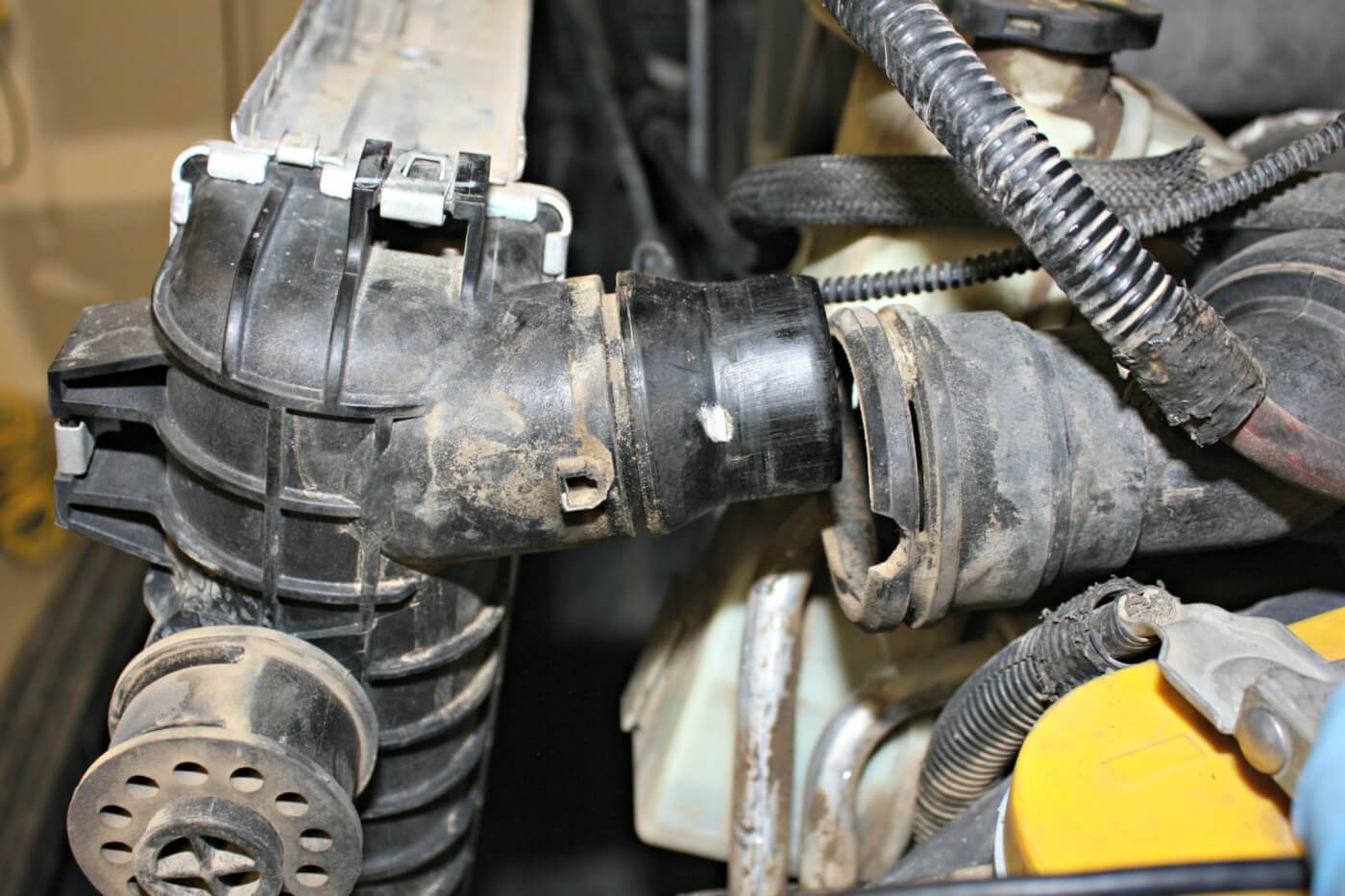 9. The factory coolant hoses can be disconnected from the radiator by simply sliding out the small metal U-clips with some pliers. Even though the radiator was drained, the lower radiator hose will still be full of coolant, so by disconnecting it from the radiator and not the engine, you should be able to avoid taking an antifreeze bath.