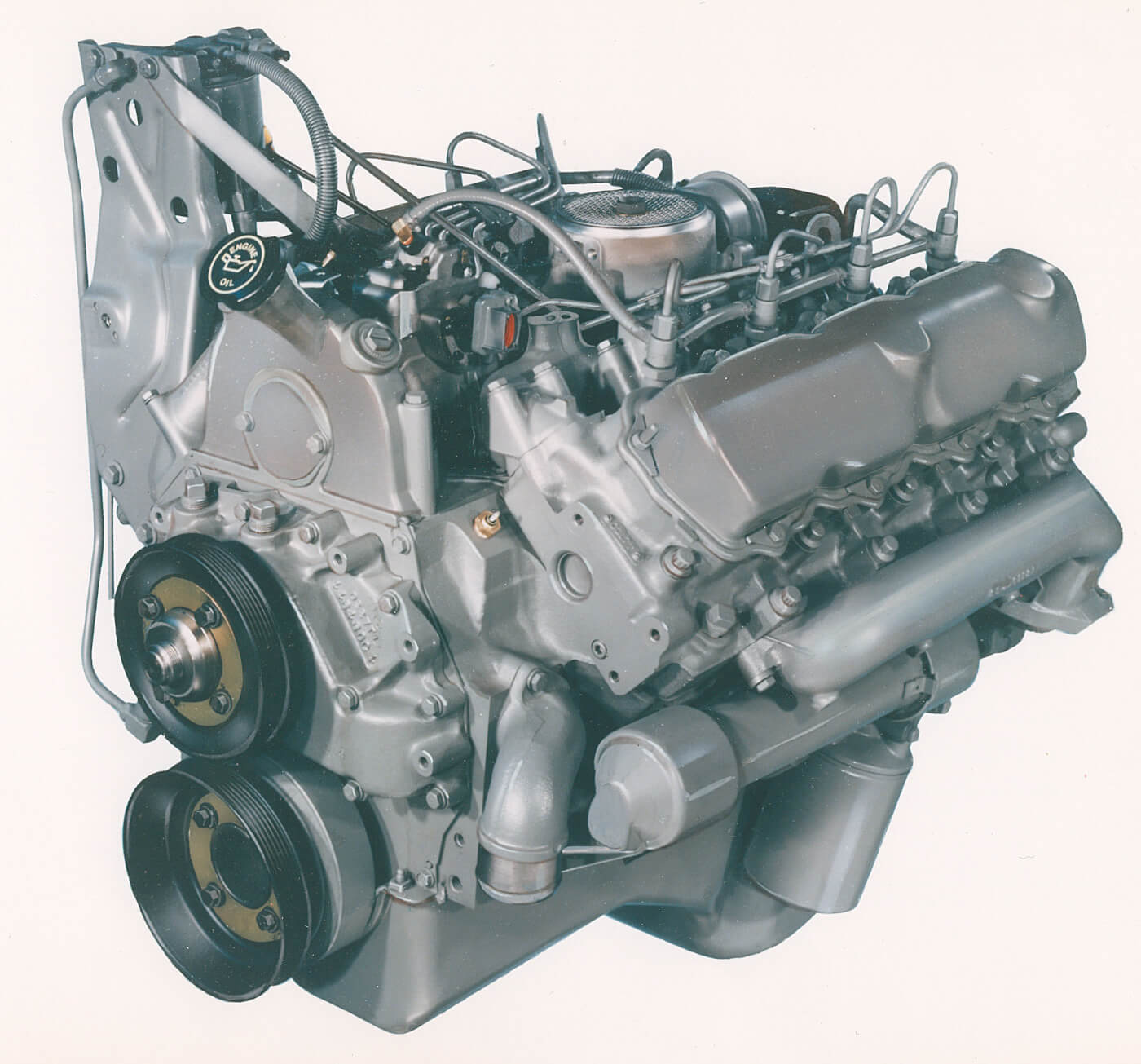 In 1988, the 7.3L IDI debuted touting a number of improvements. Power was advertised at 180 hp and torque bumped to 338 lb-ft. The 7.3L blocks can be distinguished by a 10809000C1 casting number. With the heads off, they can be identified by their round coolant ports at the corners of the block deck, as opposed to the triangular ports on the 6.9. The 7.3 also benefitted from larger head bolts (1/2-inch vs. 7/16-inch) and of course the larger bore. Thinner cylinder walls, changes in coolant flow and an increased tendency towards core shift made the 7.3 vulnerable to cavitation and pinholes from the water jacket into the cylinder. The oil filler was cast into the pump gear cover. This is a 1992 engine, which featured the serpentine belt system.