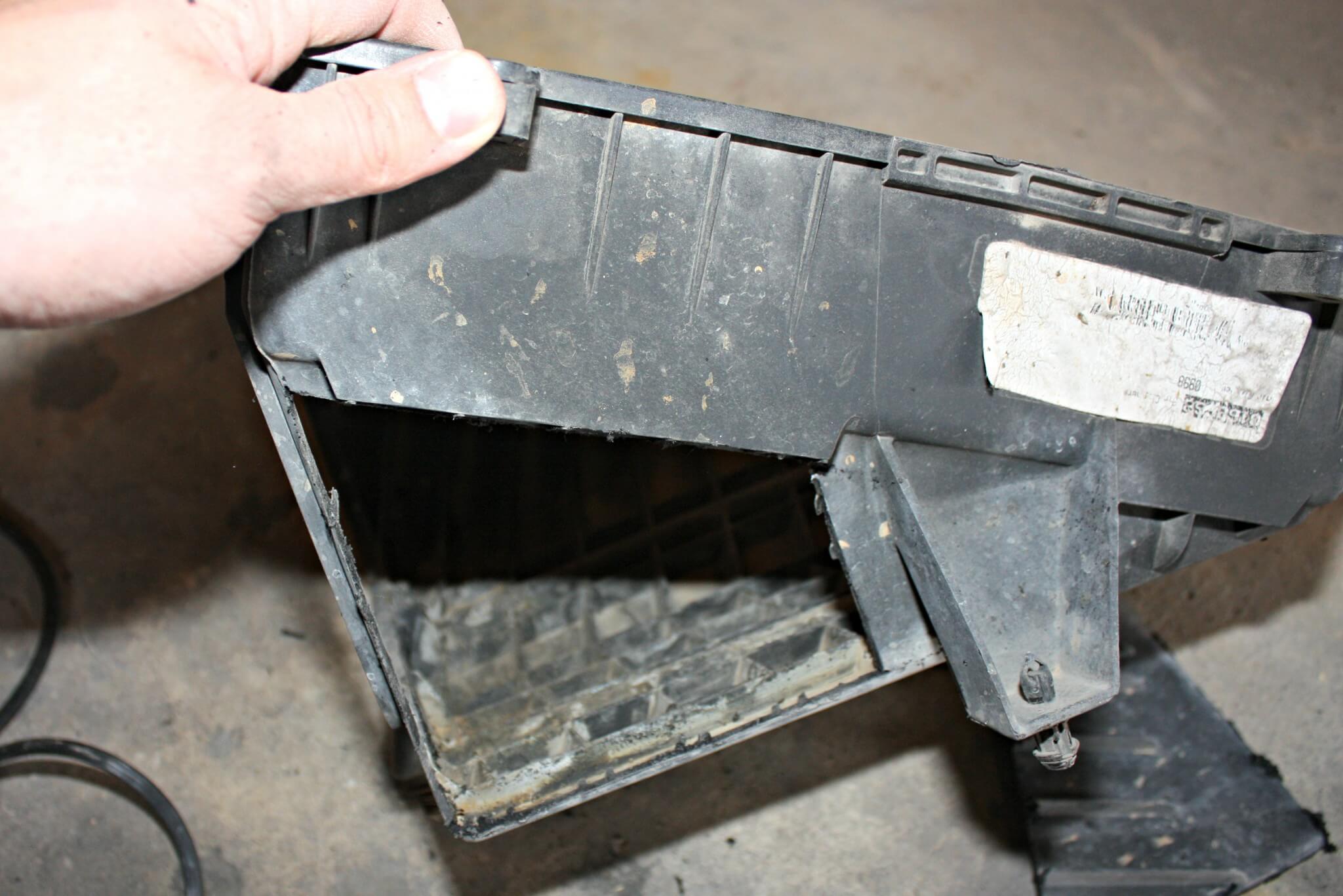 4. With the factory airbox removed from the truck, you’ll notice a small opening on the passenger side of the box where it pulls air from the inner fender well area. On the front side of the airbox, you’ll also notice a triangular-shaped section on the lower part of the box, seen here. This area can be cut out and removed to allow an additional spot for intake air to enter the box, adding some additional flow for the filter. Using a cutoff wheel, the plastic will cut easily. A small file can then be used to debur the edges before the box is reinstalled in the truck. While this may not seem like much, the added airflow can make an improvement over stock without costing you anything out of pocket.